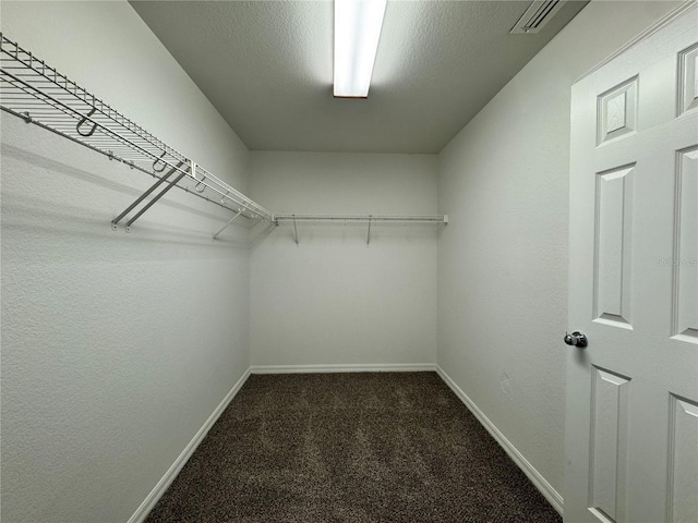 walk in closet with visible vents and dark colored carpet