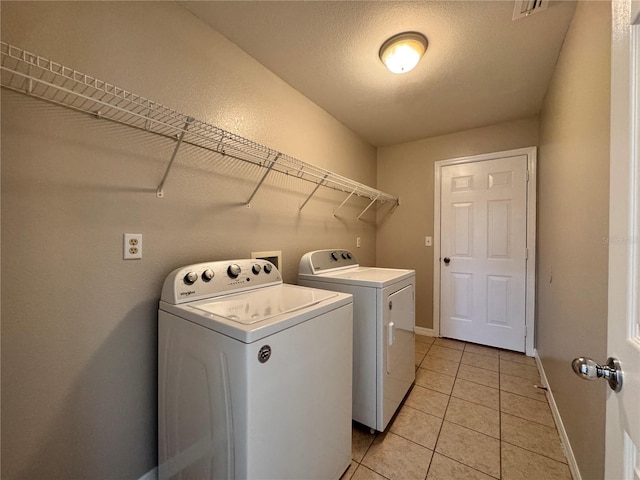 washroom with visible vents, washer and clothes dryer, light tile patterned flooring, baseboards, and laundry area