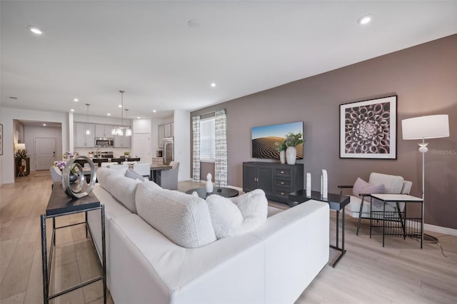 living room with recessed lighting, light wood-style flooring, and baseboards