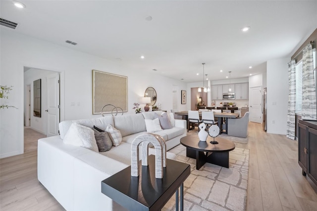 living room featuring light wood-style flooring, recessed lighting, and visible vents