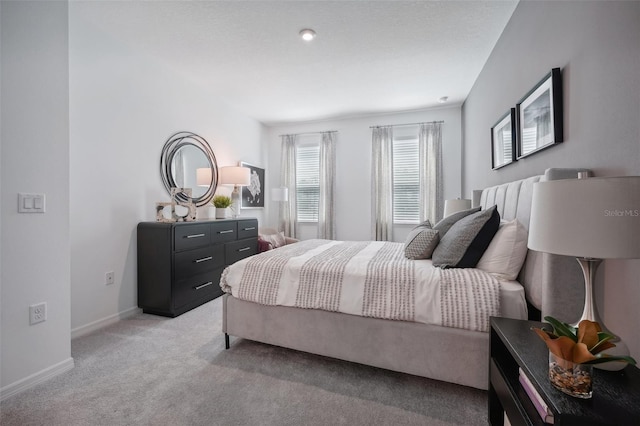 bedroom with baseboards and light colored carpet