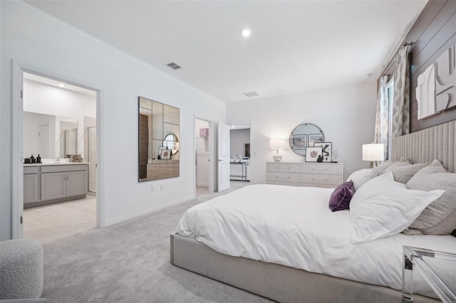 bedroom featuring visible vents, light carpet, baseboards, and ensuite bathroom