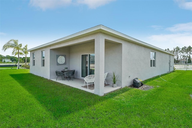 rear view of property with a patio area, stucco siding, and a yard