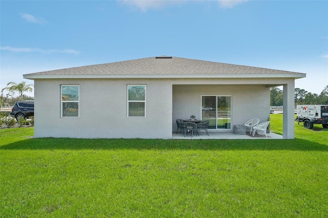 rear view of property with stucco siding, a patio, a lawn, and a shingled roof