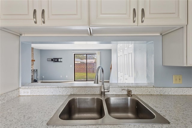 kitchen featuring a sink, light stone counters, and cream cabinetry