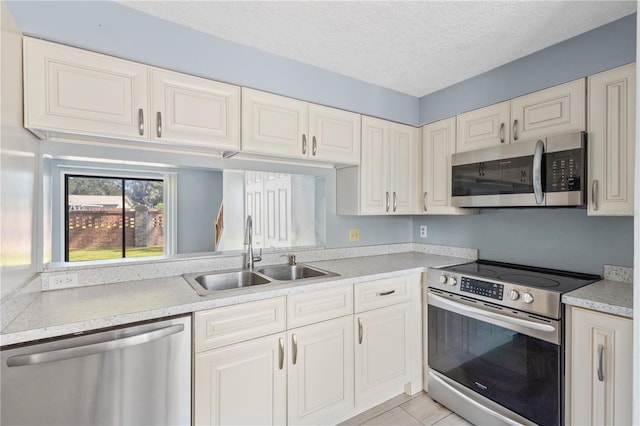 kitchen featuring light countertops, light tile patterned floors, stainless steel appliances, a textured ceiling, and a sink