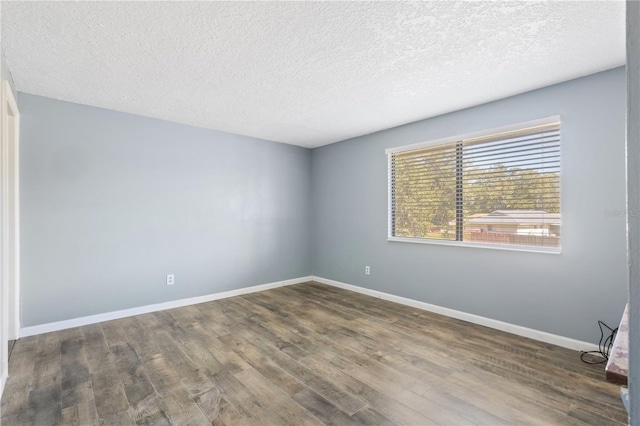 spare room featuring baseboards, a textured ceiling, and wood finished floors