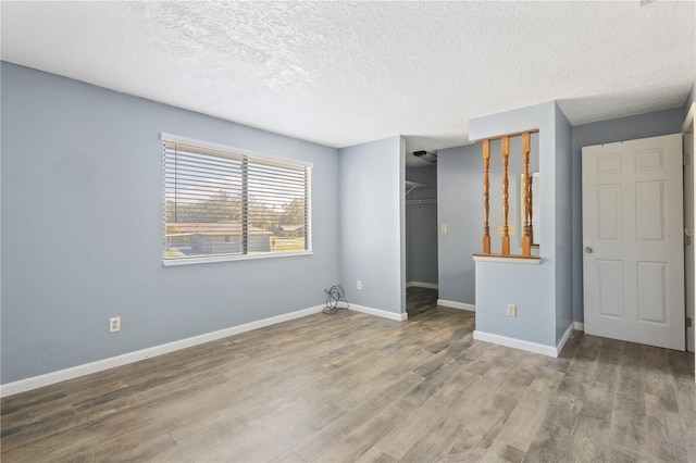 unfurnished bedroom with a closet, baseboards, a textured ceiling, and wood finished floors