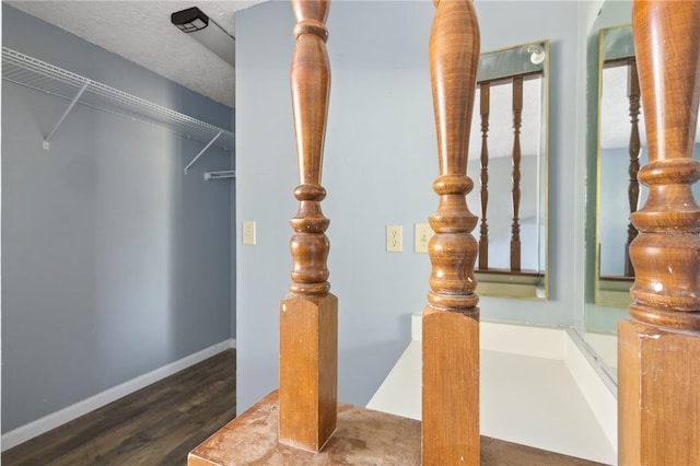 staircase with a textured ceiling, baseboards, and wood finished floors