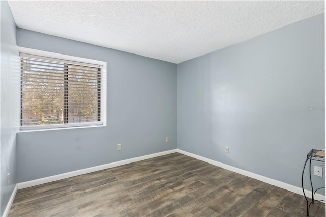 empty room with wood finished floors, baseboards, and a textured ceiling