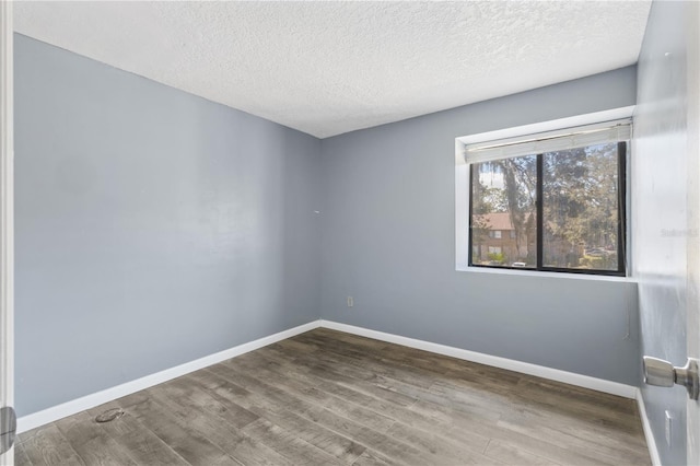 empty room featuring baseboards, a textured ceiling, and wood finished floors