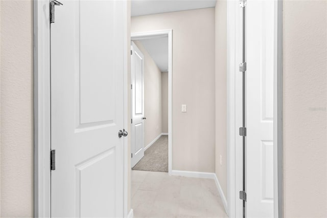 corridor featuring light tile patterned floors and baseboards