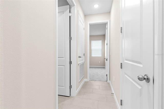 corridor featuring light tile patterned floors and baseboards