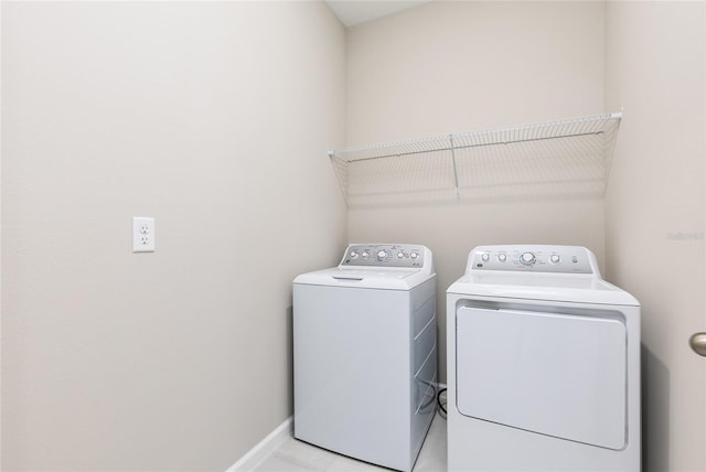 clothes washing area with washer and dryer, baseboards, and laundry area