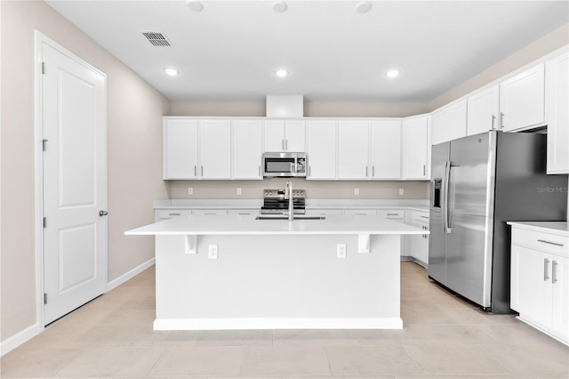 kitchen featuring visible vents, a kitchen island with sink, a sink, light countertops, and appliances with stainless steel finishes