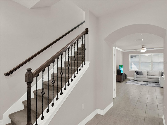 stairs featuring arched walkways, tile patterned flooring, baseboards, and ceiling fan