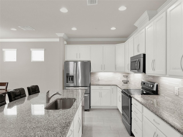 kitchen with visible vents, a sink, decorative backsplash, appliances with stainless steel finishes, and crown molding