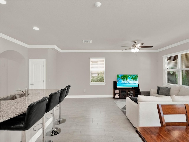 living room featuring visible vents, arched walkways, ceiling fan, and crown molding