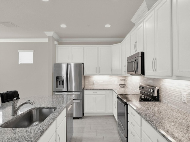 kitchen with ornamental molding, a sink, backsplash, white cabinetry, and stainless steel appliances