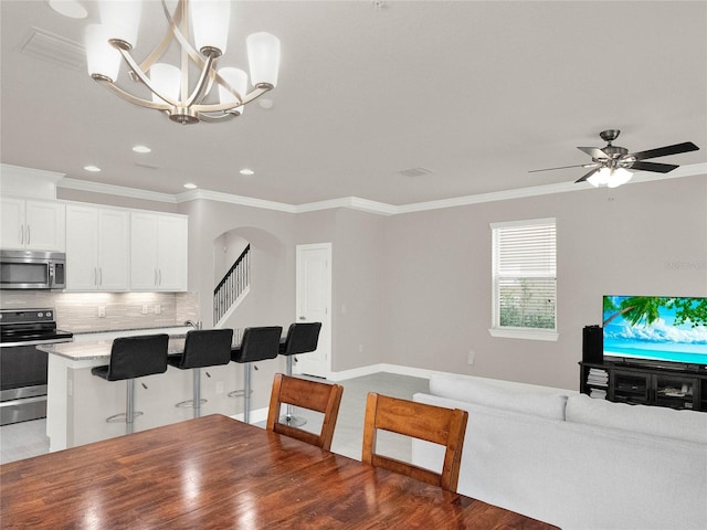 interior space featuring ornamental molding, backsplash, open floor plan, arched walkways, and appliances with stainless steel finishes