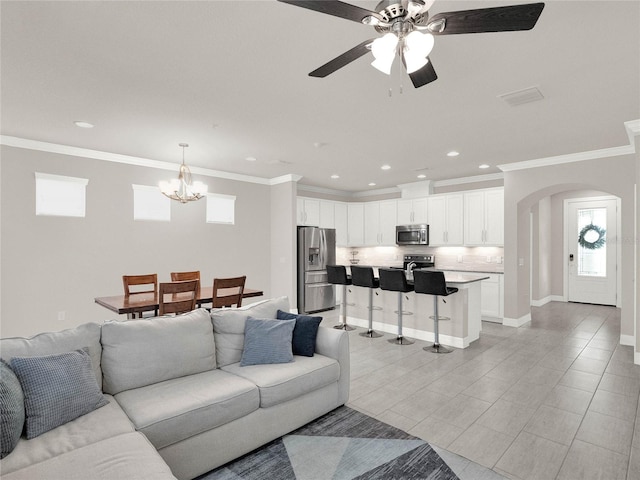 living area with baseboards, recessed lighting, arched walkways, ornamental molding, and ceiling fan with notable chandelier