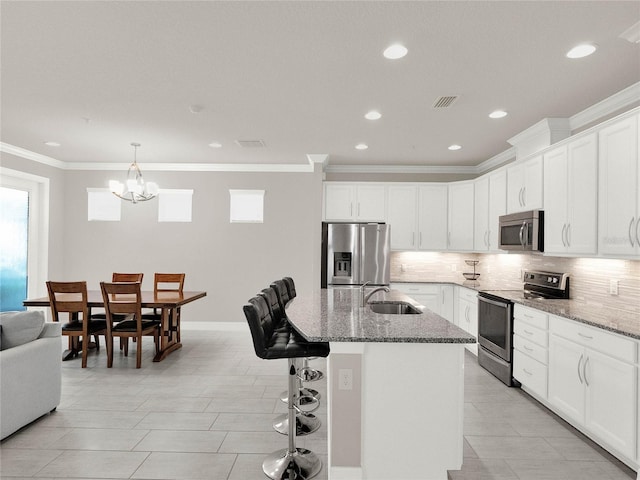 kitchen featuring a sink, backsplash, stainless steel appliances, stone counters, and a chandelier