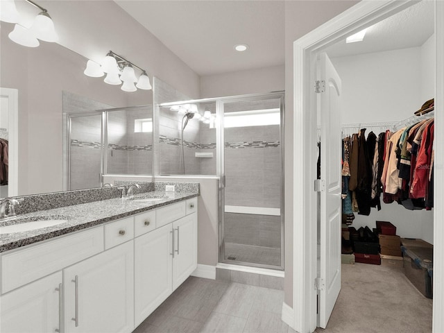 bathroom with a walk in closet, a shower stall, and a sink