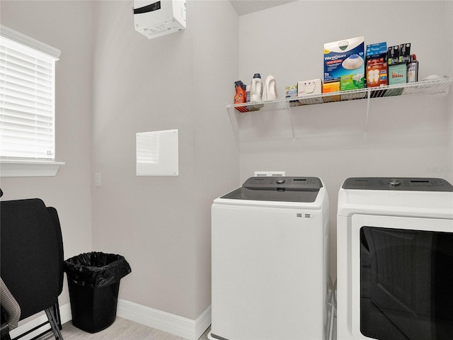 clothes washing area with baseboards, separate washer and dryer, and laundry area