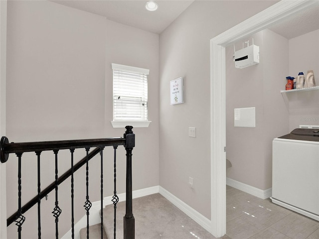 hallway featuring washer / dryer, an upstairs landing, and baseboards