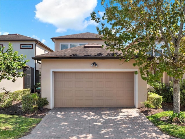 view of front of property with stucco siding, driveway, an attached garage, and a shingled roof