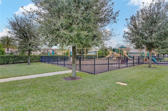 view of community with a lawn, playground community, and fence