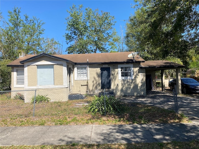 bungalow-style home with an attached carport, fence, roof with shingles, and stucco siding