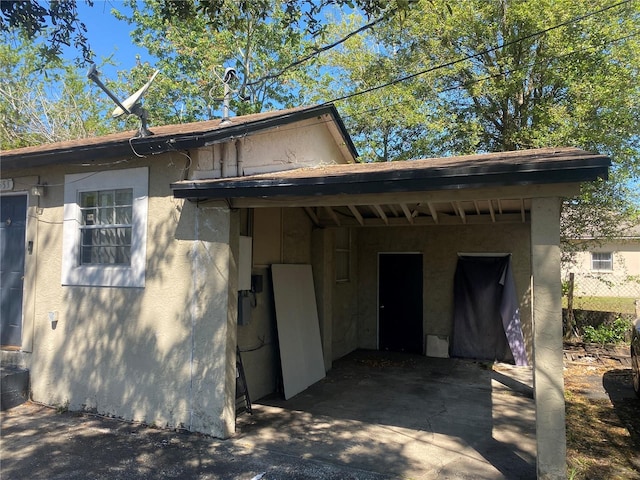 back of property featuring a carport and stucco siding