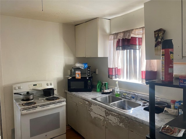 kitchen featuring a sink, electric range, black microwave, and light countertops