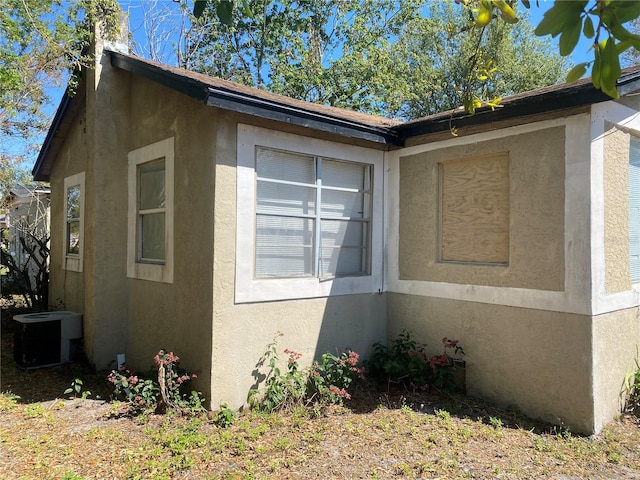 view of side of home featuring cooling unit and stucco siding