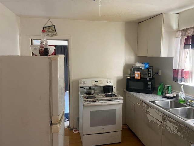 kitchen with white appliances, light countertops, and a sink