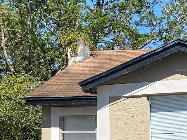 exterior details featuring stucco siding and a shingled roof