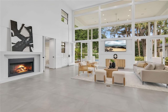 living room with a high ceiling and a glass covered fireplace