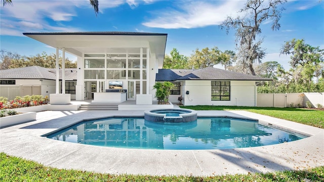 back of house with a fenced backyard, a sunroom, a pool with connected hot tub, and a patio area