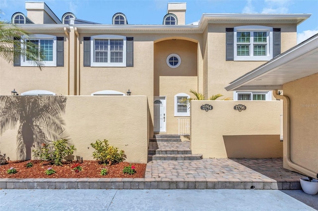 townhome / multi-family property with stucco siding, a fenced front yard, and a gate