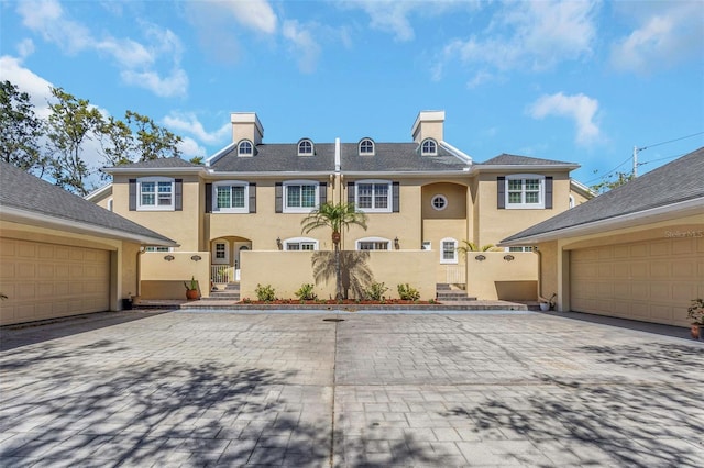 multi unit property with a fenced front yard, stucco siding, a chimney, and a garage