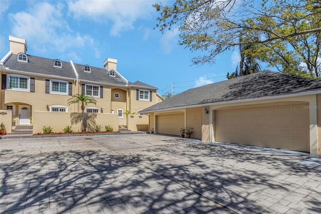 view of front of home with stucco siding, driveway, and a garage