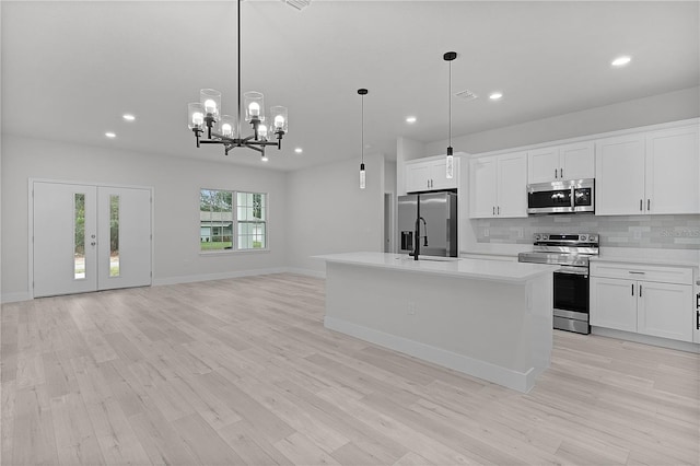 kitchen featuring light wood-type flooring, a sink, tasteful backsplash, appliances with stainless steel finishes, and light countertops