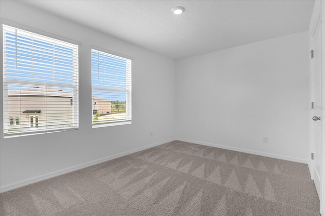 unfurnished room featuring baseboards and light carpet