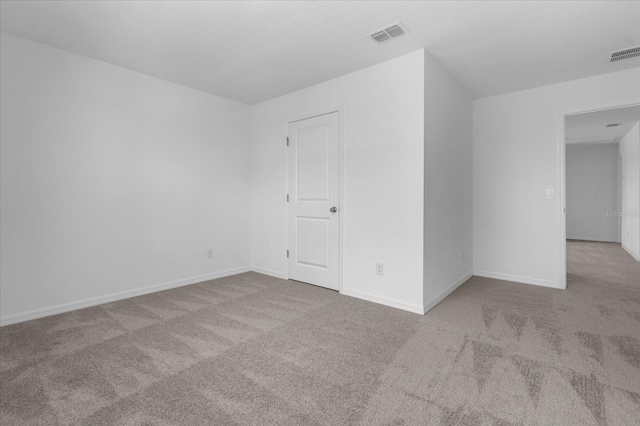 unfurnished room featuring carpet, visible vents, and baseboards