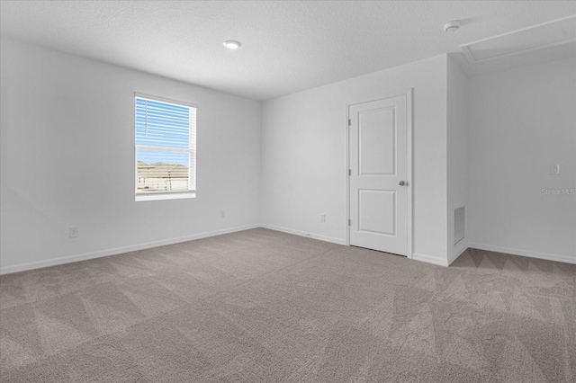 carpeted spare room with visible vents, a textured ceiling, and baseboards