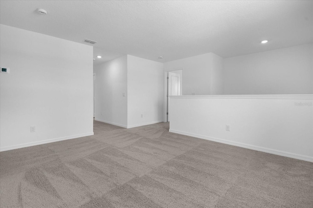 empty room featuring visible vents, carpet, baseboards, recessed lighting, and a textured ceiling