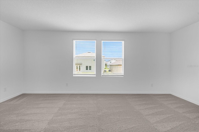 carpeted empty room with a textured ceiling and baseboards