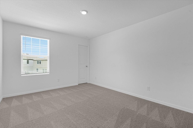 carpeted empty room featuring baseboards and a textured ceiling