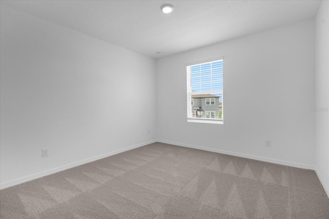 spare room with baseboards and carpet